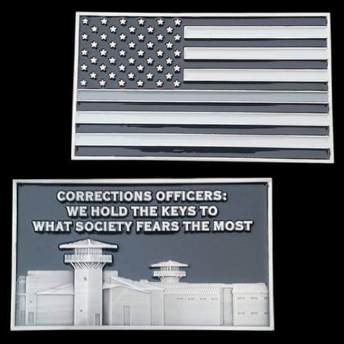 US flag above a sign that reads: 'Corrections Officers: We hold the keys to what society fears the most' with a prison facility illustration behind it